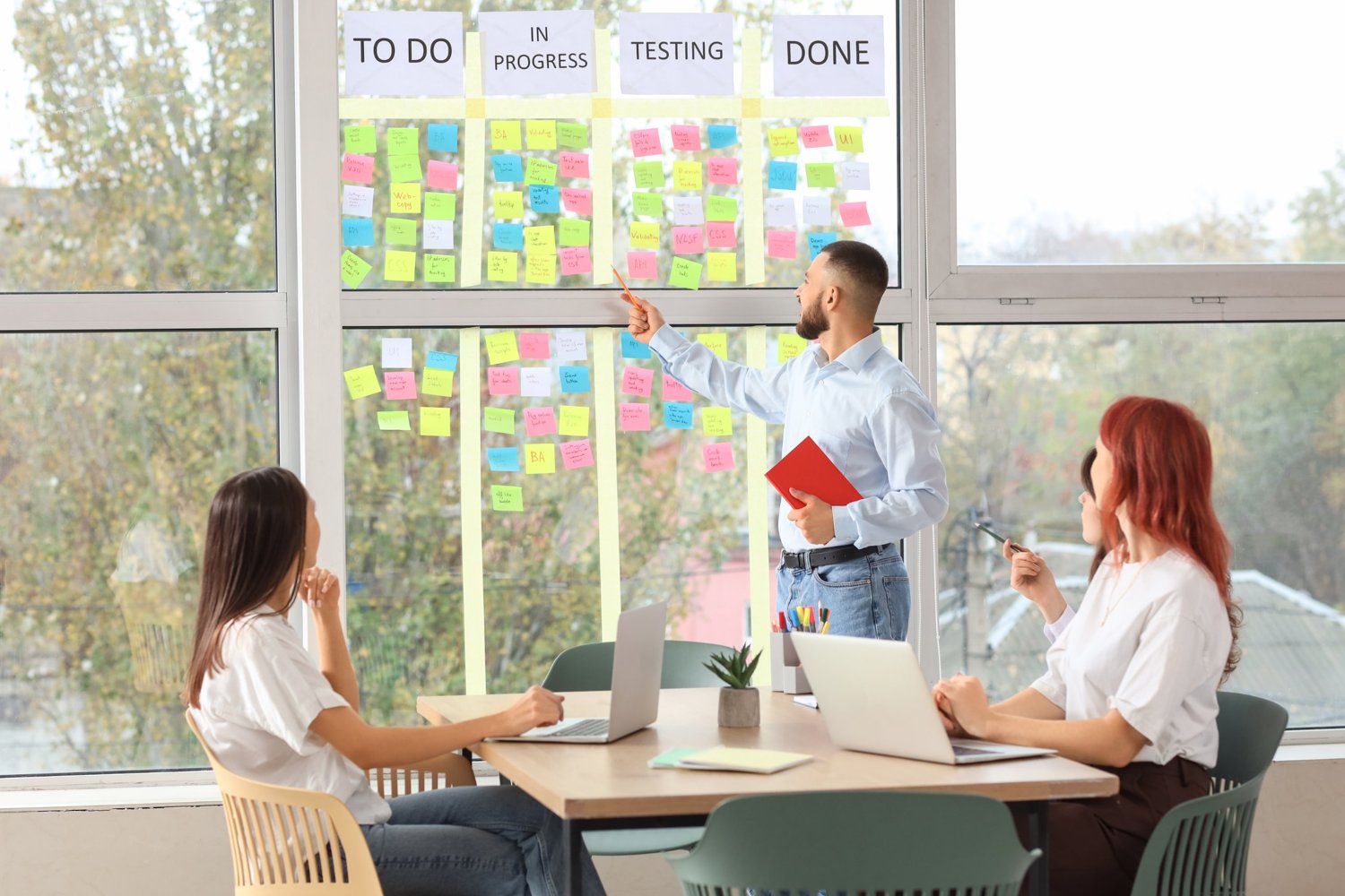 A consultant presenting a project board to colleagues: Design, Develop and Deploy