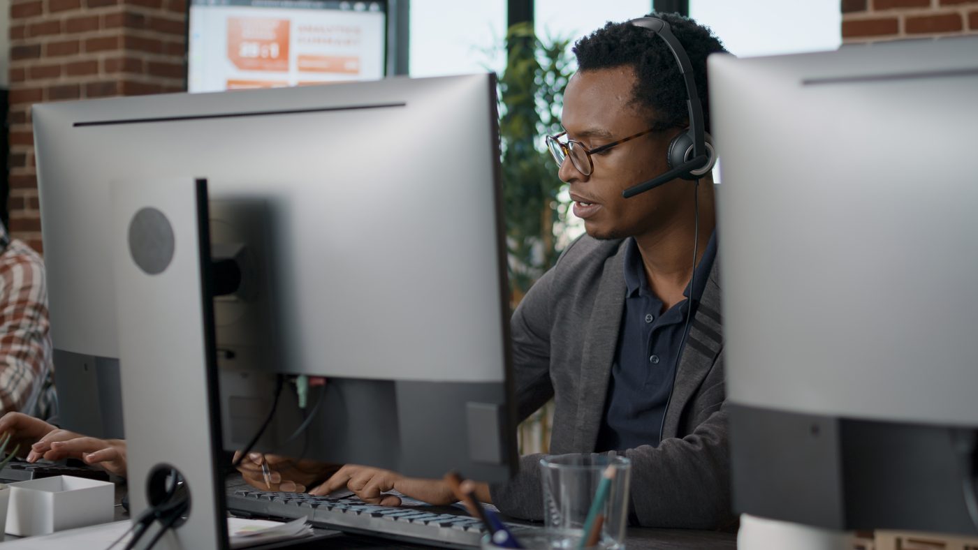 A support consultant wearing a headset, working at his desk